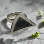 Triangular silver ring with textured center on a marble surface